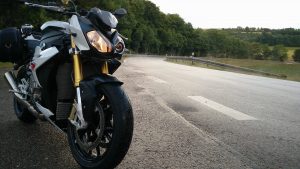 Bild: Motorrad vor Straße, von der Dampf aufsteigt.